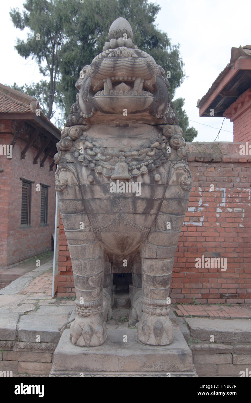 A stylised carved stone lion stands guard outside a temple in the Bhaktapur locality of Kathmandu, Nepal Stock Photo