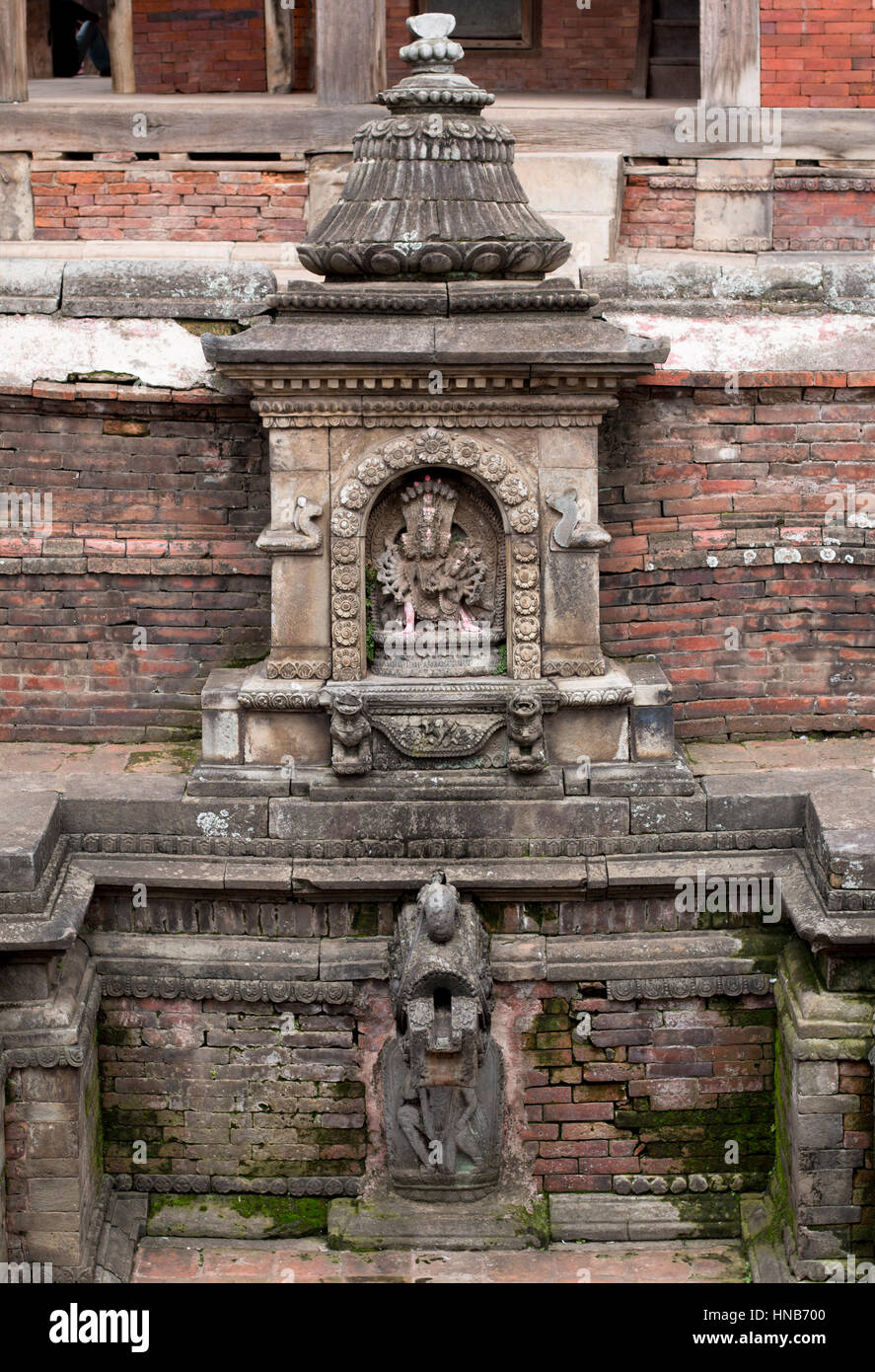 Stone carving of Vishnu, a Hindu god, in a temple in Bhaktapur, Kathmandu, next to the water pond Stock Photo