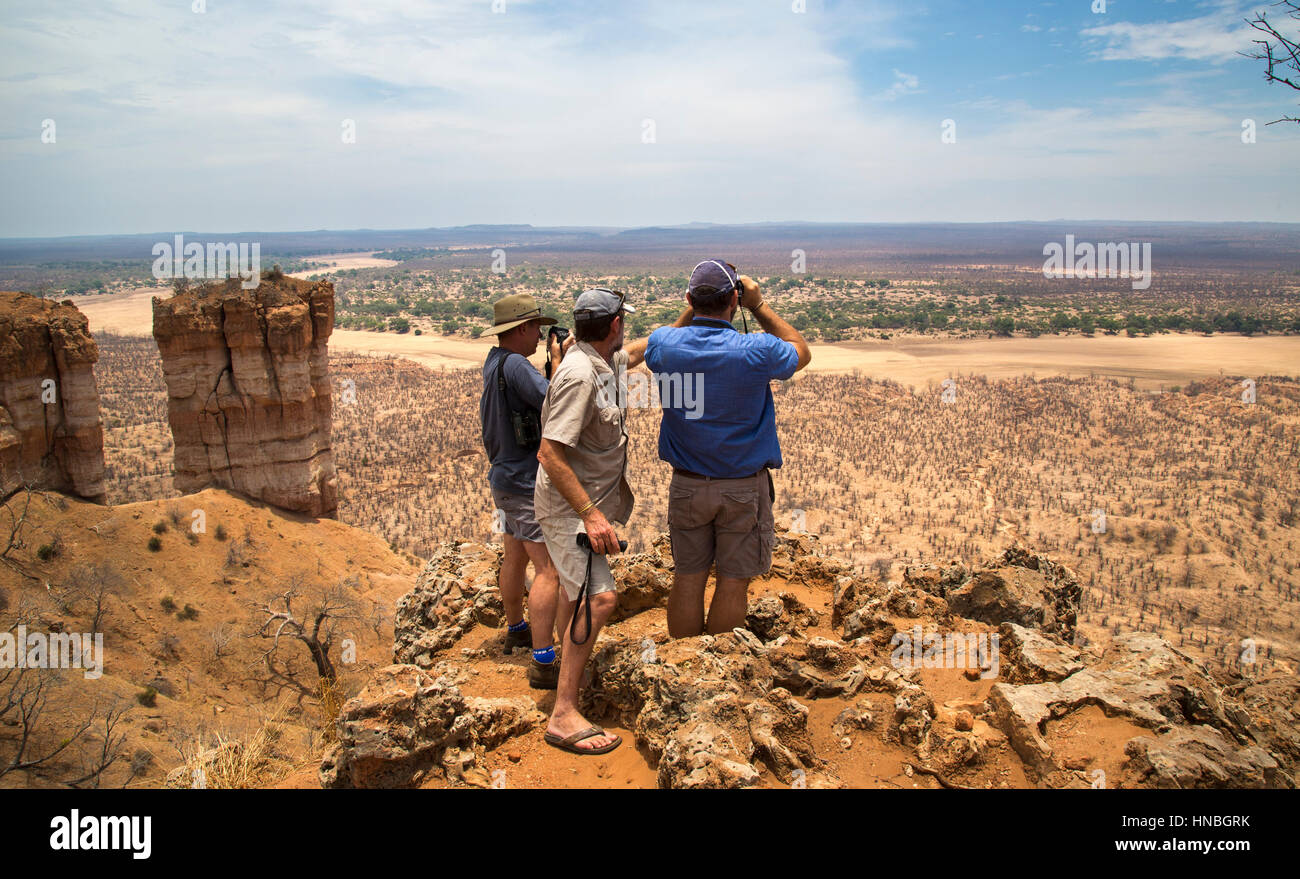 Three travellers looking out over the landscape and the Runde riverbed from the viewpoint on Chilojo Cliffs in Gonarezhou Stock Photo