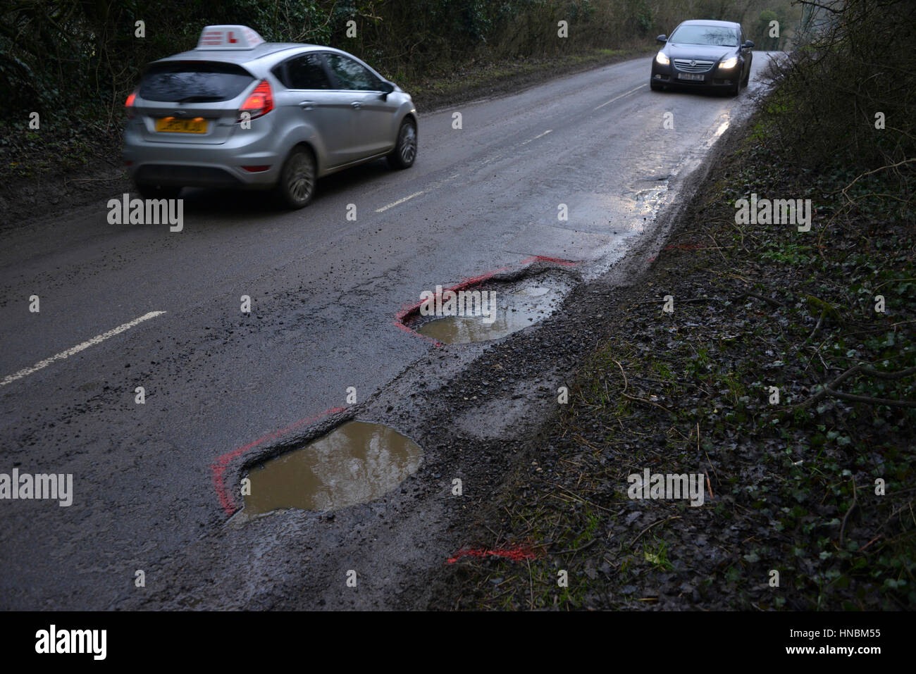 Car seeking to avoid a pothole on the side of the road in the north Oxfordshire village of Hook Norton Stock Photo