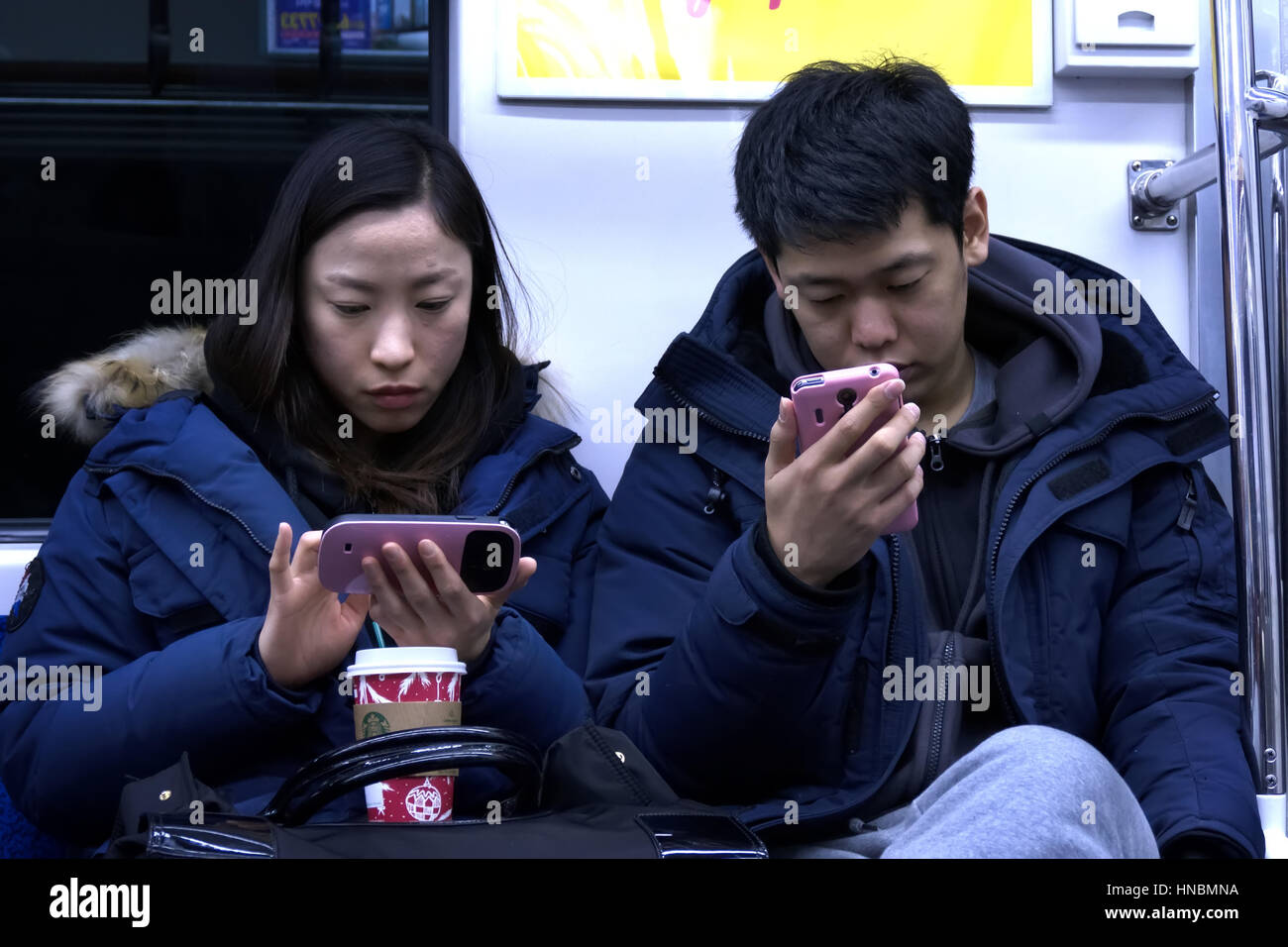 Asian people, young man and woman, Korean youth with mobile phone, traveling on subway train. Seoul, South Korea, Asia Stock Photo