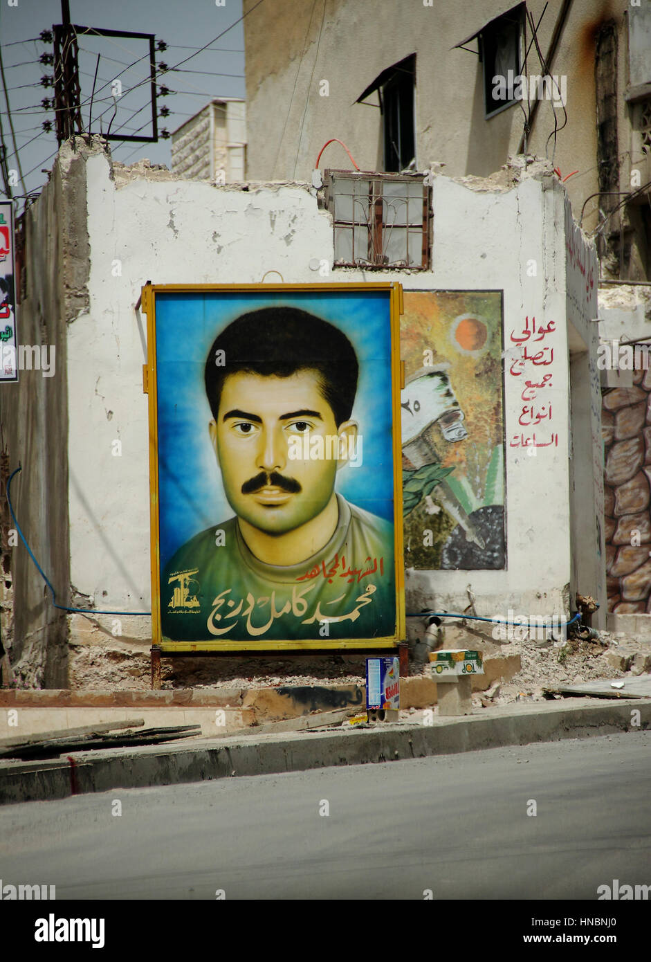 A billboard depicts a martyr from the 2006 war with Israel in the south of Lebanon, near Tyre. The symbol on the bottom left indicates his association Stock Photo