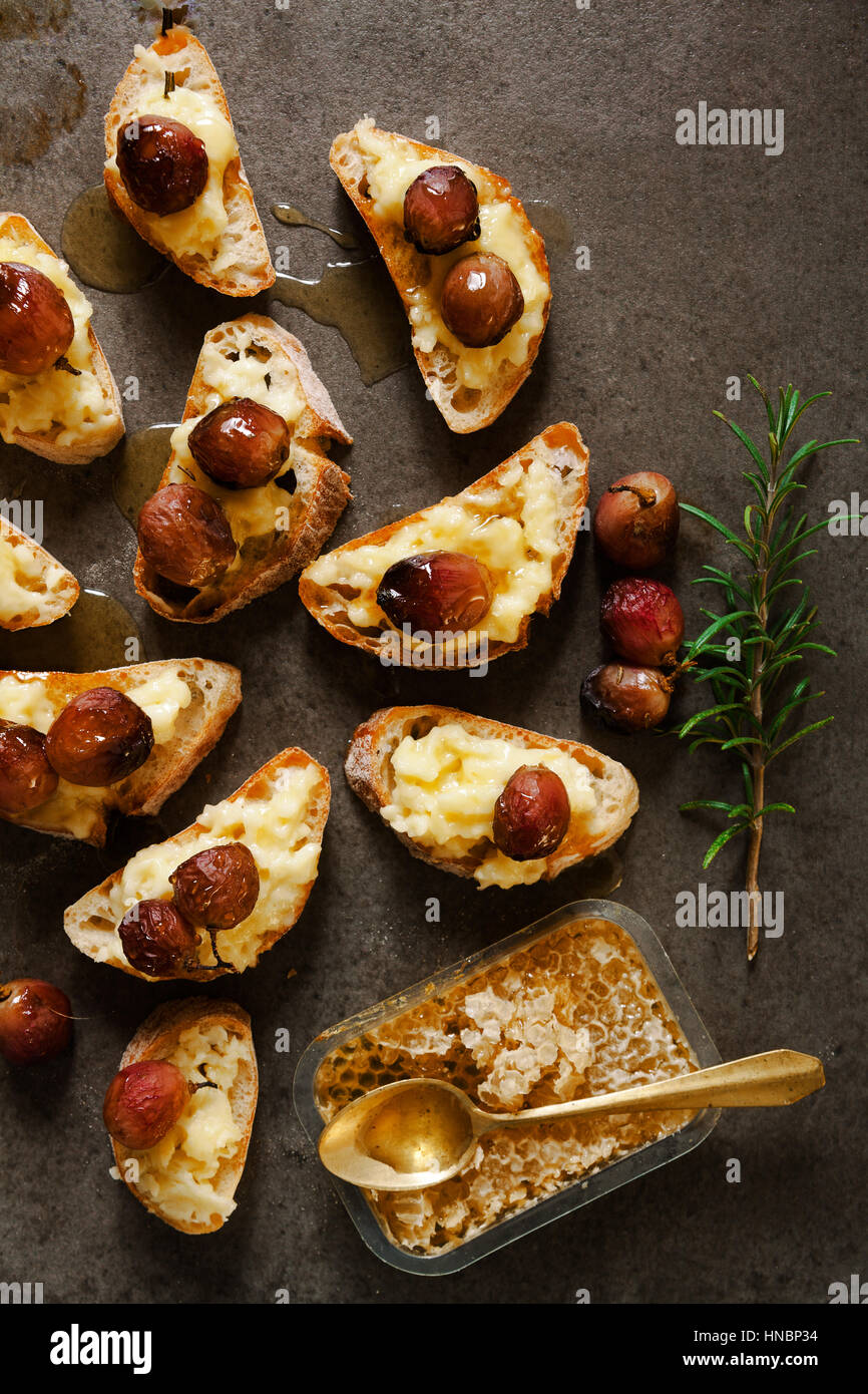 Canapes with baked Camembert cheese, grapes and honey bruschette on a wooden table Stock Photo