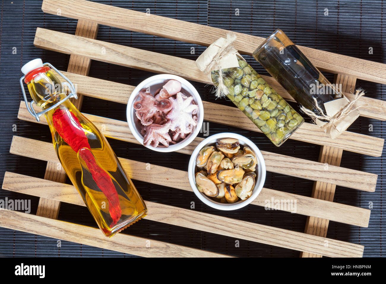Bottle of olive oil with chili pepper, black olives and capers in jar
