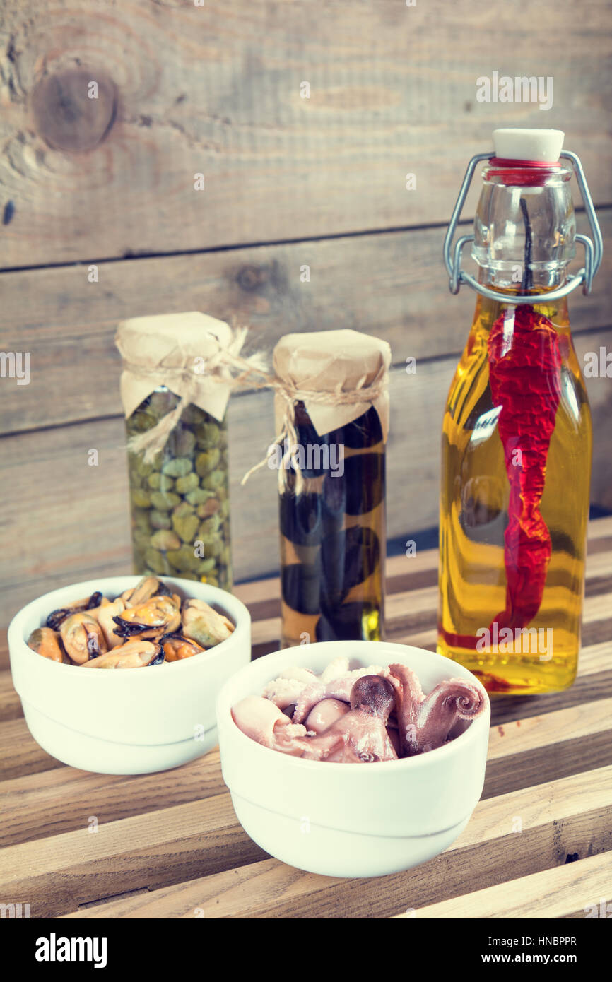 Octopus in ceramic bowls and bottle of olive oil with chili pepper