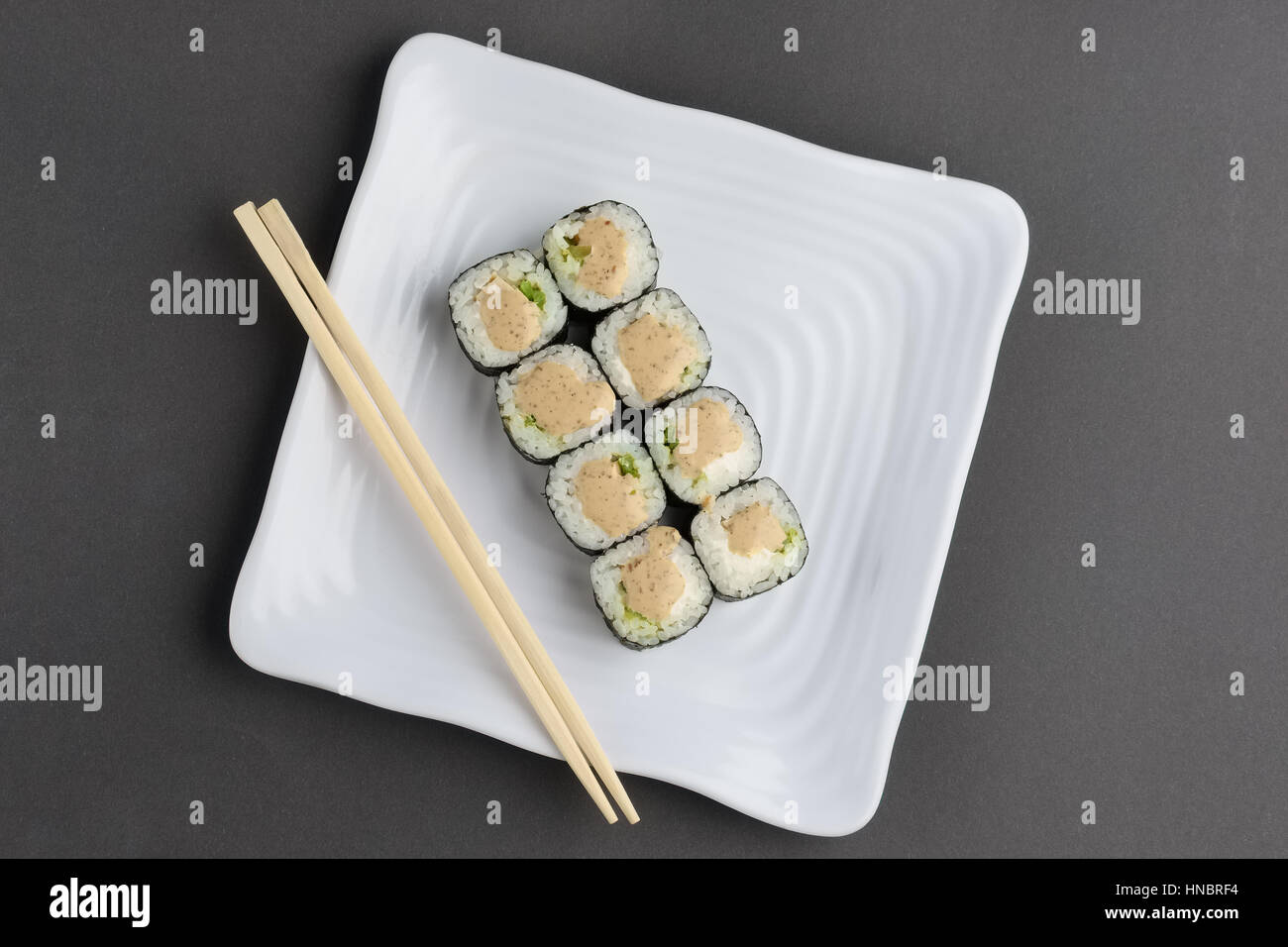 roll with cucumber and chicken on square plate with nut sauce Stock Photo