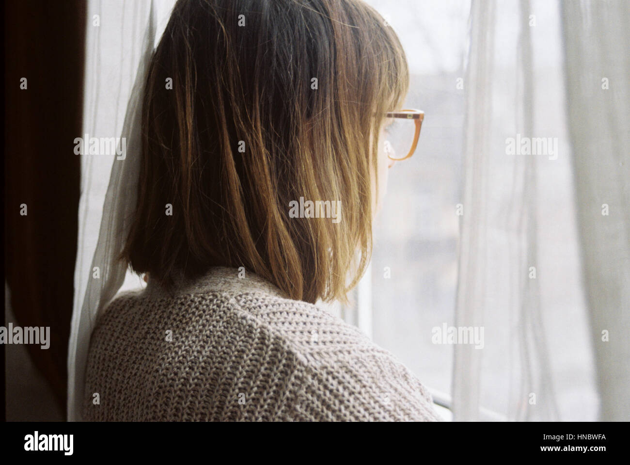 Woman looking out of window curtains hi-res stock photography and ...