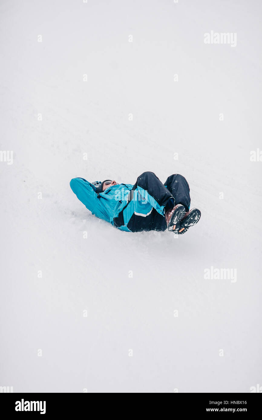 Man sliding down snow covered hill on his back Stock Photo Alamy