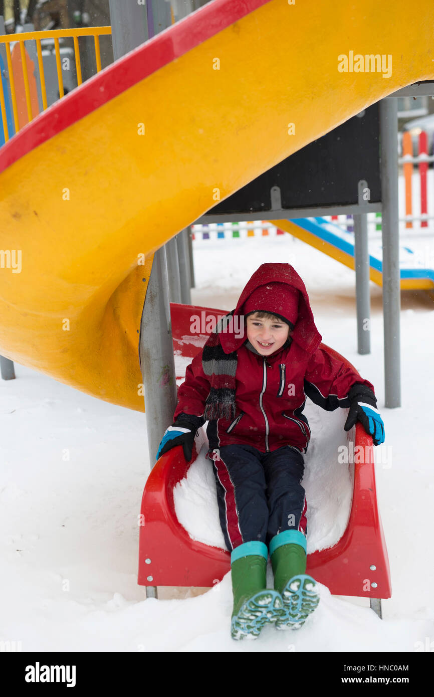 Boy sliding down a slide in snow Stock Photo Alamy