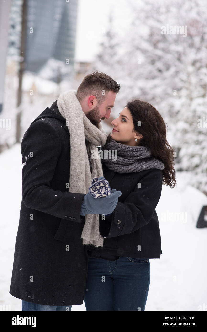Couple standing in the snow holding hands and looking at each other Stock Photo