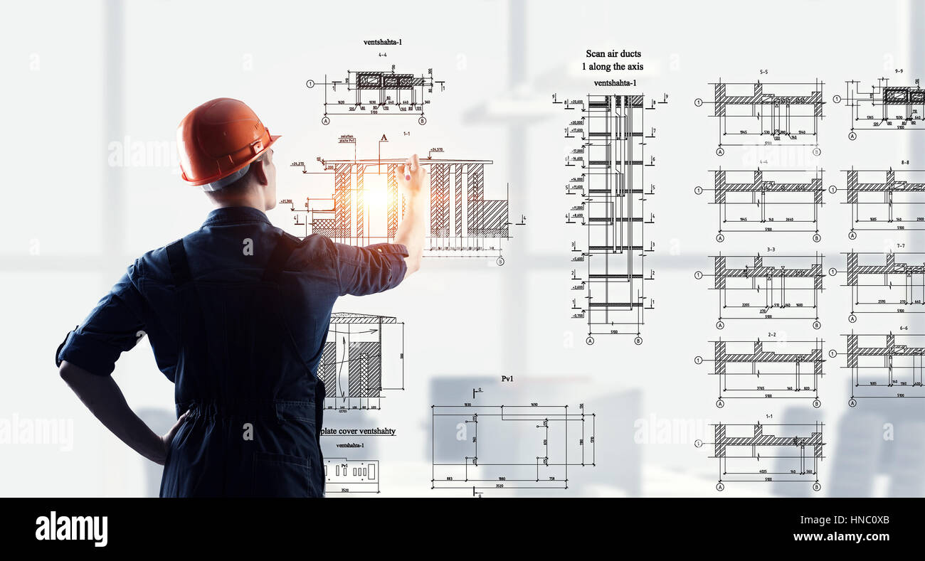 Rear view of engineer man in helmet and overall sketching construction ...