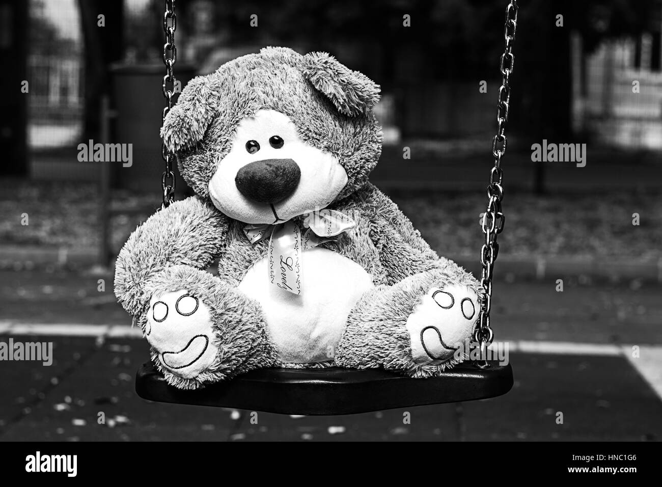 Depressed Fluffy Soft Teddy Bear Toy sitting on cradle in the park Stock Photo