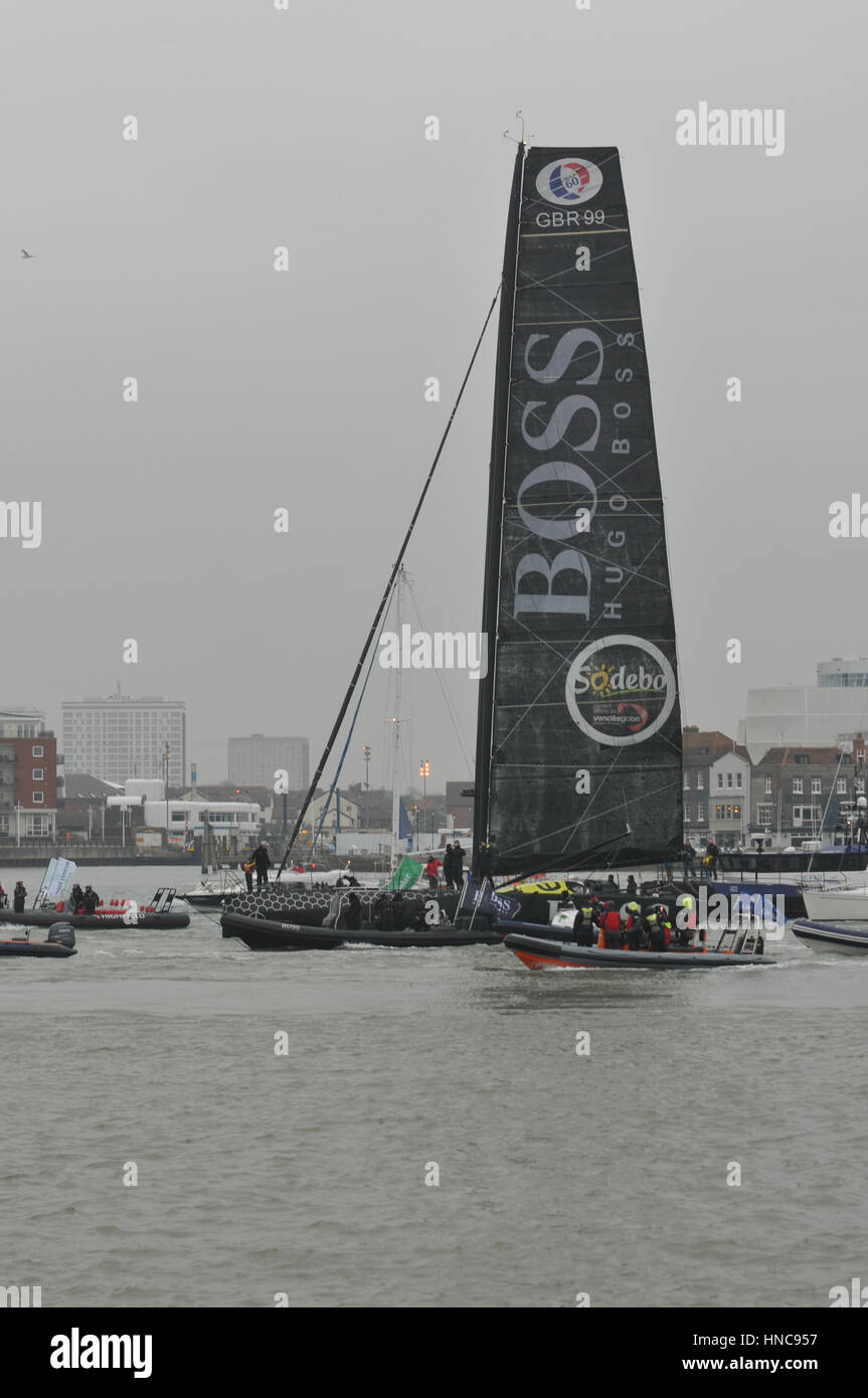 Alex Tomson arriving in Gosport in England after being the runner up in the Vendee Globe round the world yacht race with flotilla of small boats and large crowd on the shore side Stock Photo