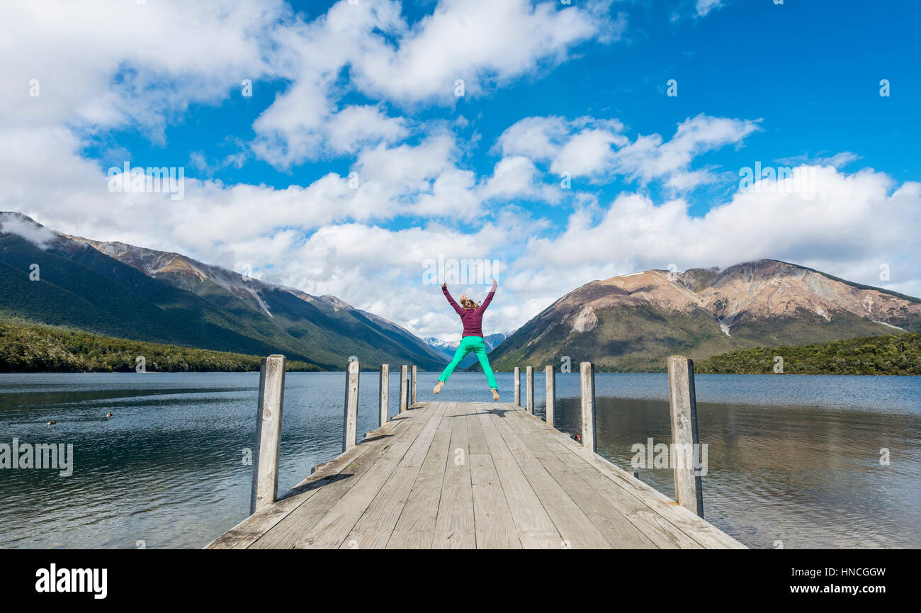 Woman jumping in the air, dock on Lake Rotoiti, Nelson Lakes National Park, Tasman District, Southland, New Zealand Stock Photo