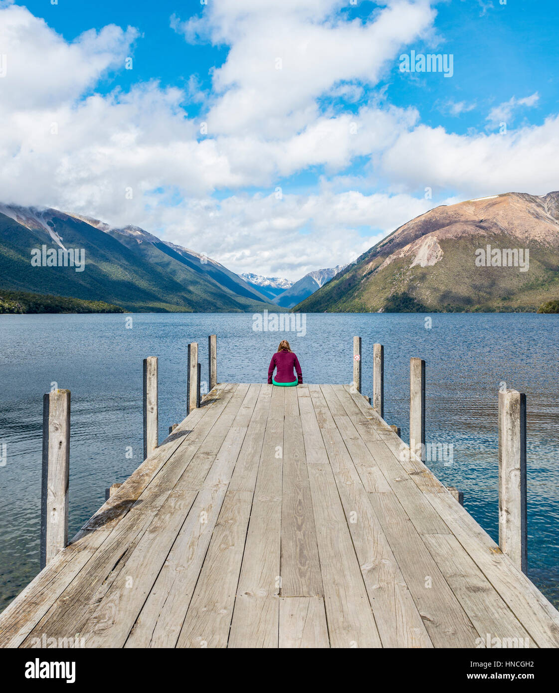 Woman sitting on dock, view of Lake Rotoiti, Nelson Lakes National Park, Tasman District, Southland, New Zealand Stock Photo