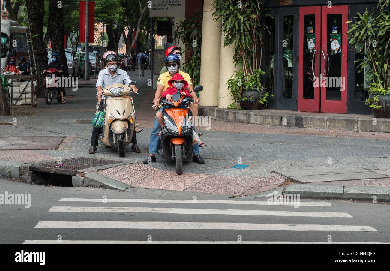 Saigon, Vietnam, Nov 2016 - Three passengers on a scooter ride on the pavement to avoid traffic in Ho Chi Minh city. Stock Photo