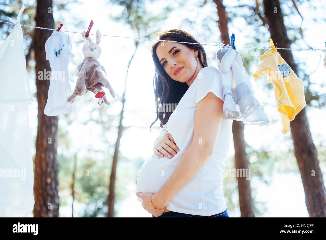 woman hanging baby clothes in linen rope outdoors Stock Photo