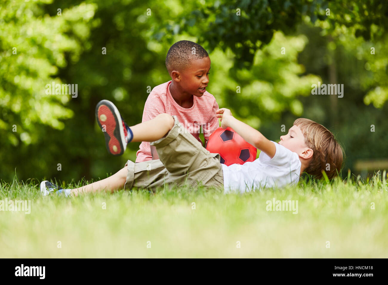 Two boys playing soccer together in the park in summer Stock Photo