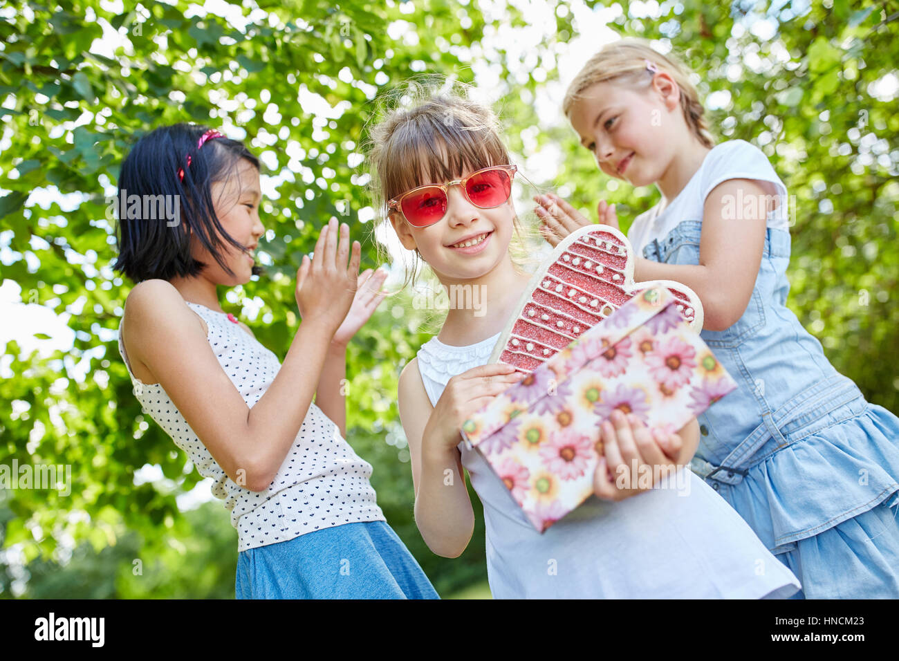 Girls clap their hands for birthday girl at party in summer Stock Photo