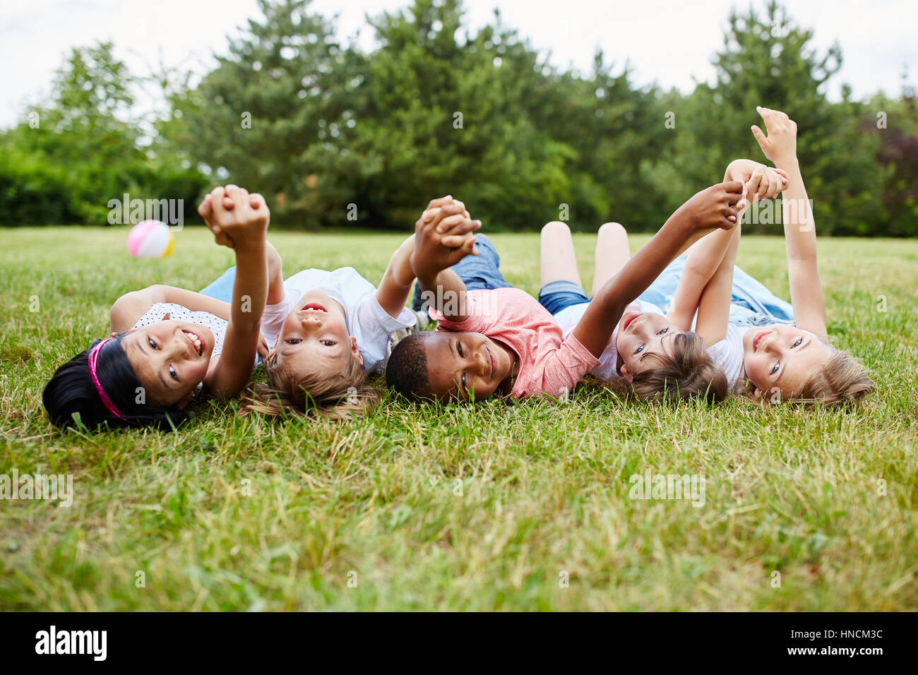 Interracial kids show togetherness holding hands as friends in summer Stock Photo