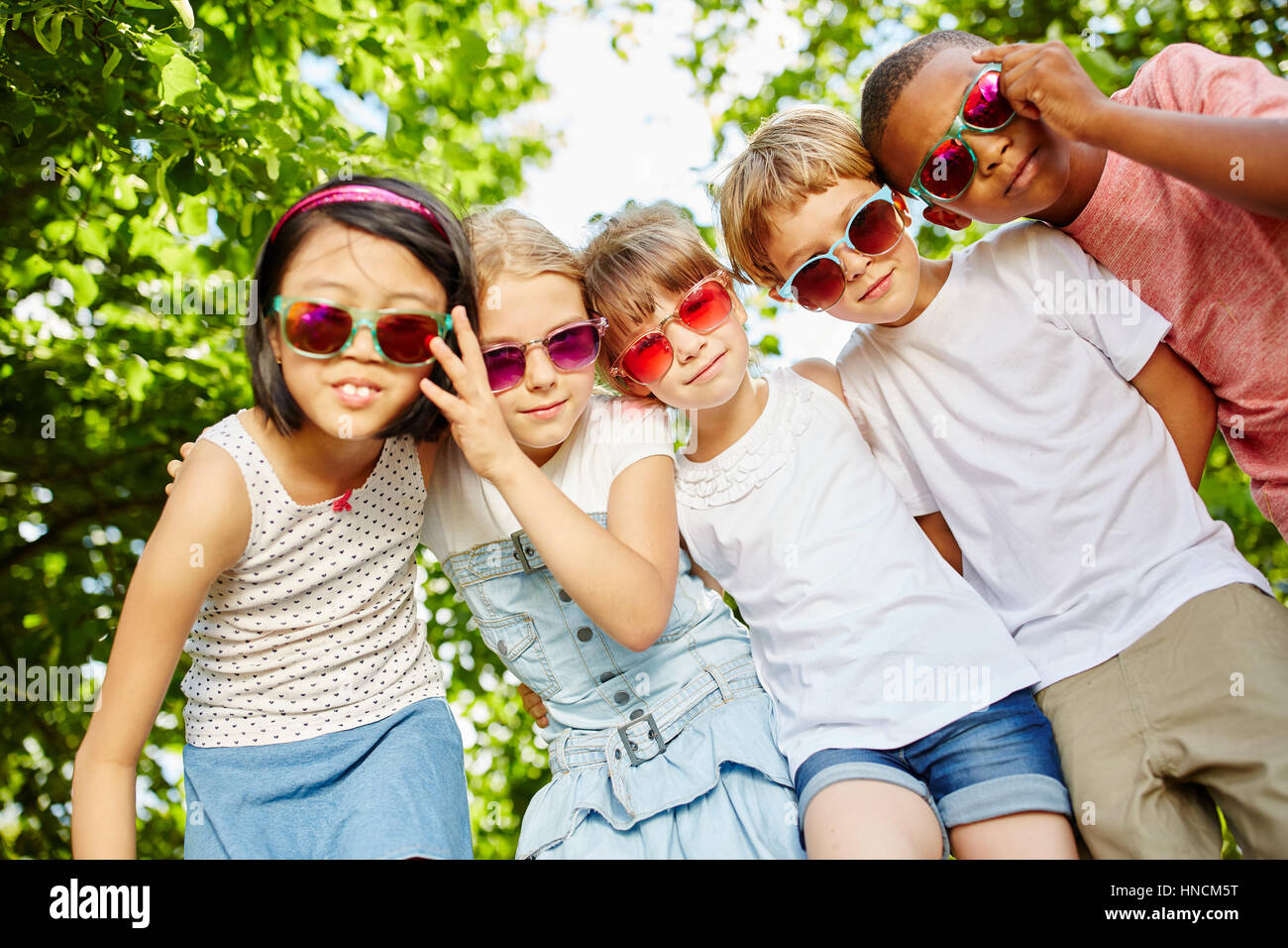 Children as friends in cool interracial team together at the park in summer Stock Photo