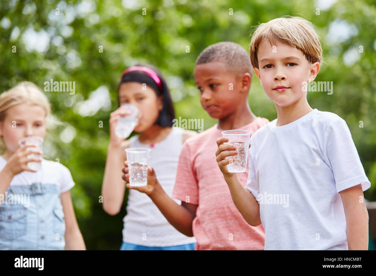 Group of kids drink water as healthy refreshment in summer Stock Photo