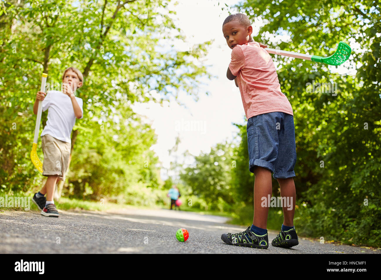 Two kids play street hockey as summer activity in kindergarten Stock Photo