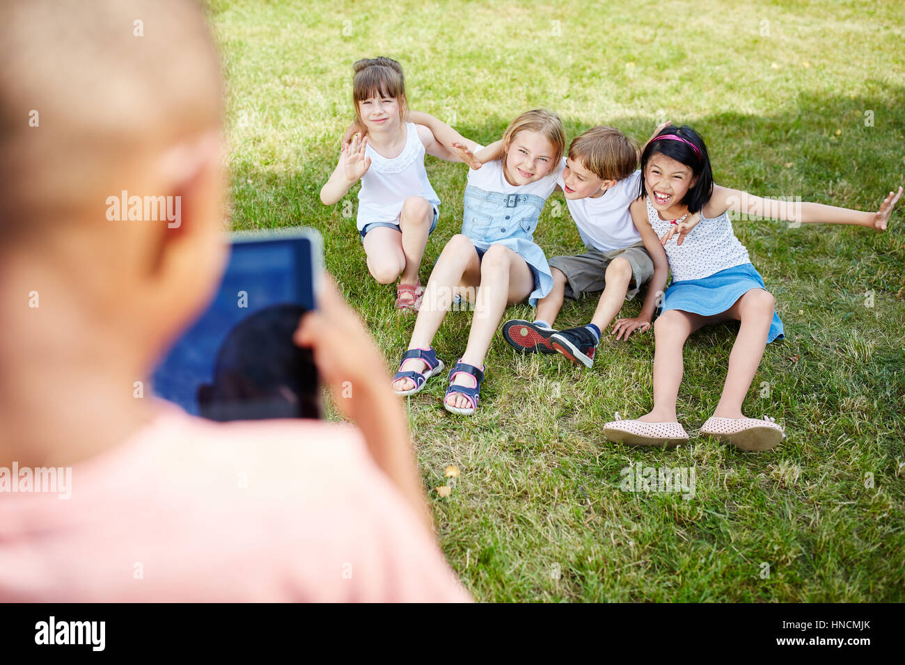 Boy takes group picture of kids at meadow in summer Stock Photo
