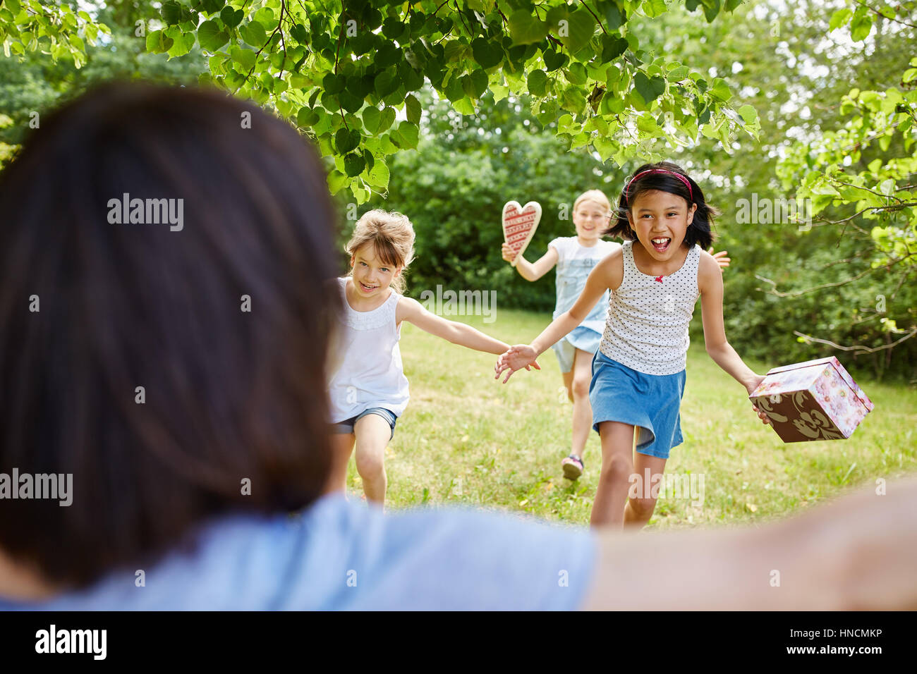 Children as friends run with joy with birthday presents to party Stock Photo
