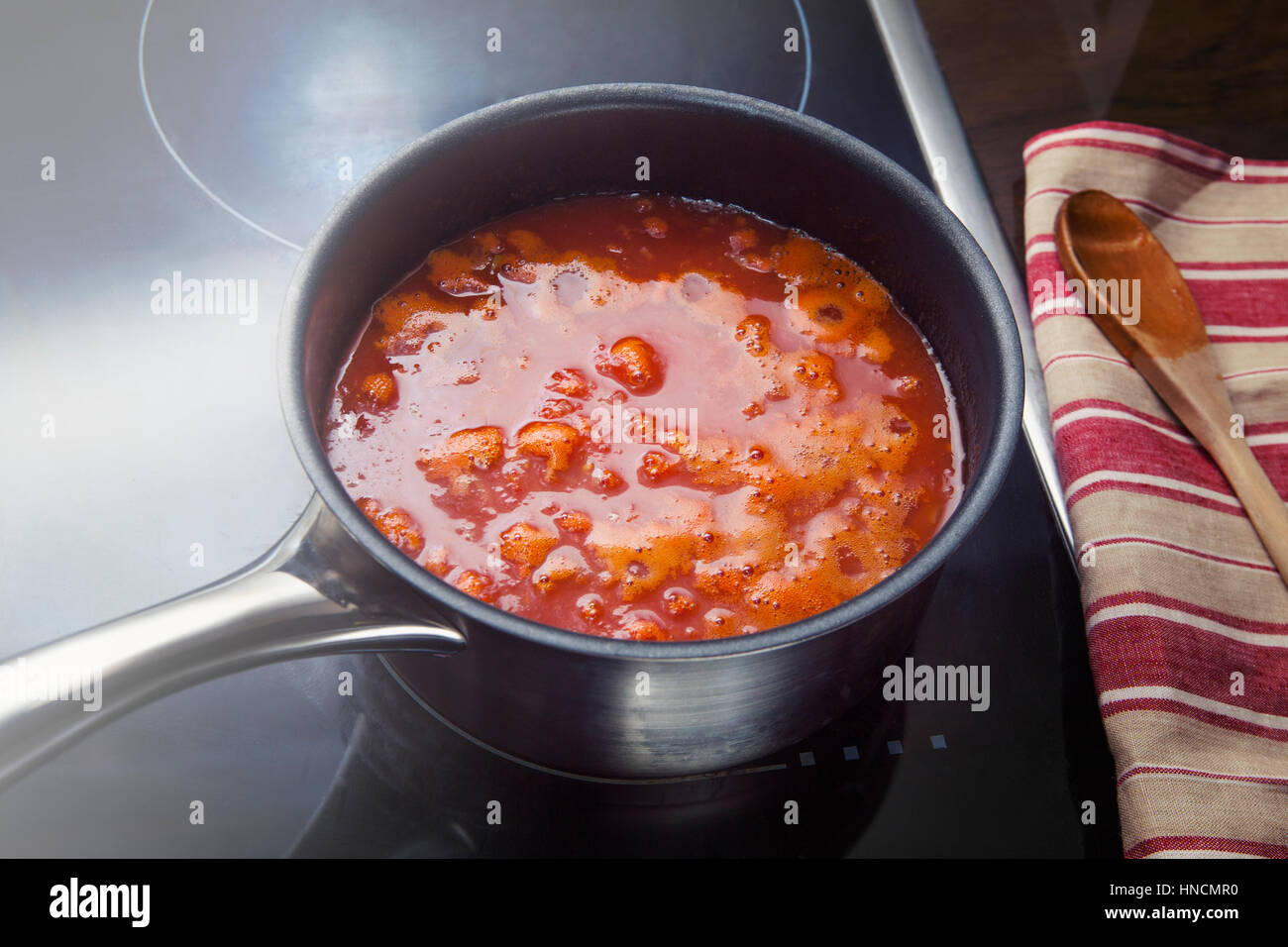 Tomato sauce simmering into the pan in the kitchen Stock Photo - Alamy