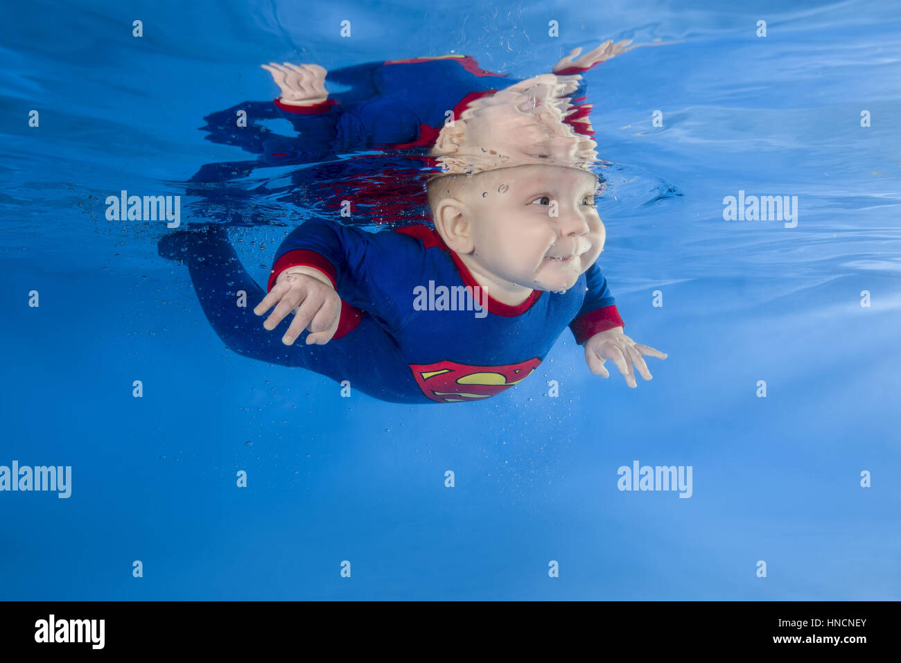 Litle boy in Superman costume posing under water in swimming pool, Odessa, Ukraine Stock Photo