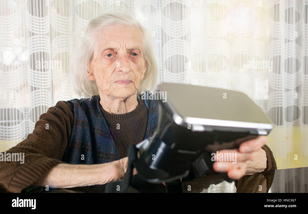 Grandma trying to use VR goggles at home Stock Photo