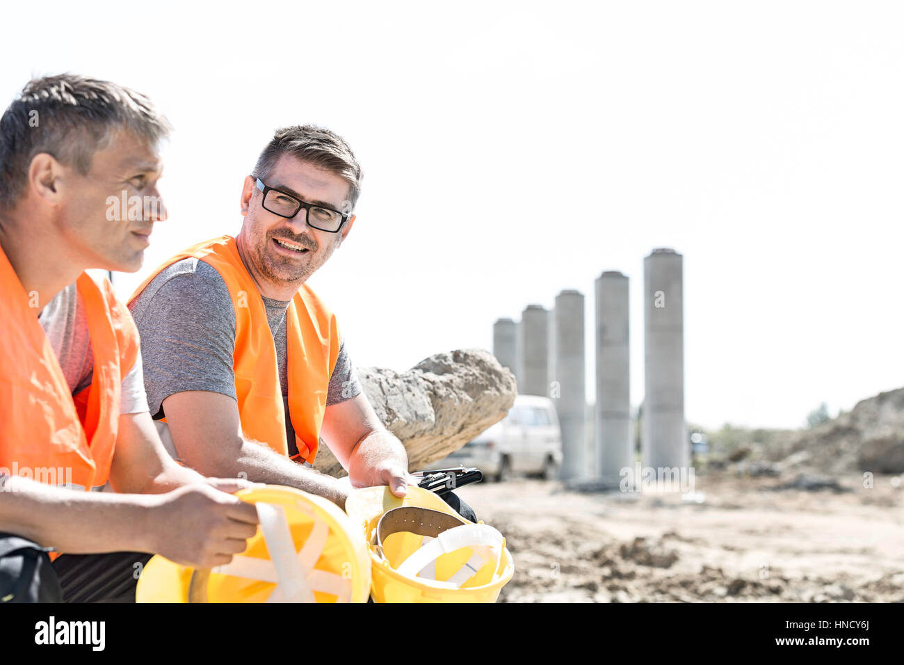 Smiling supervisor sitting with colleague at construction site Stock Photo