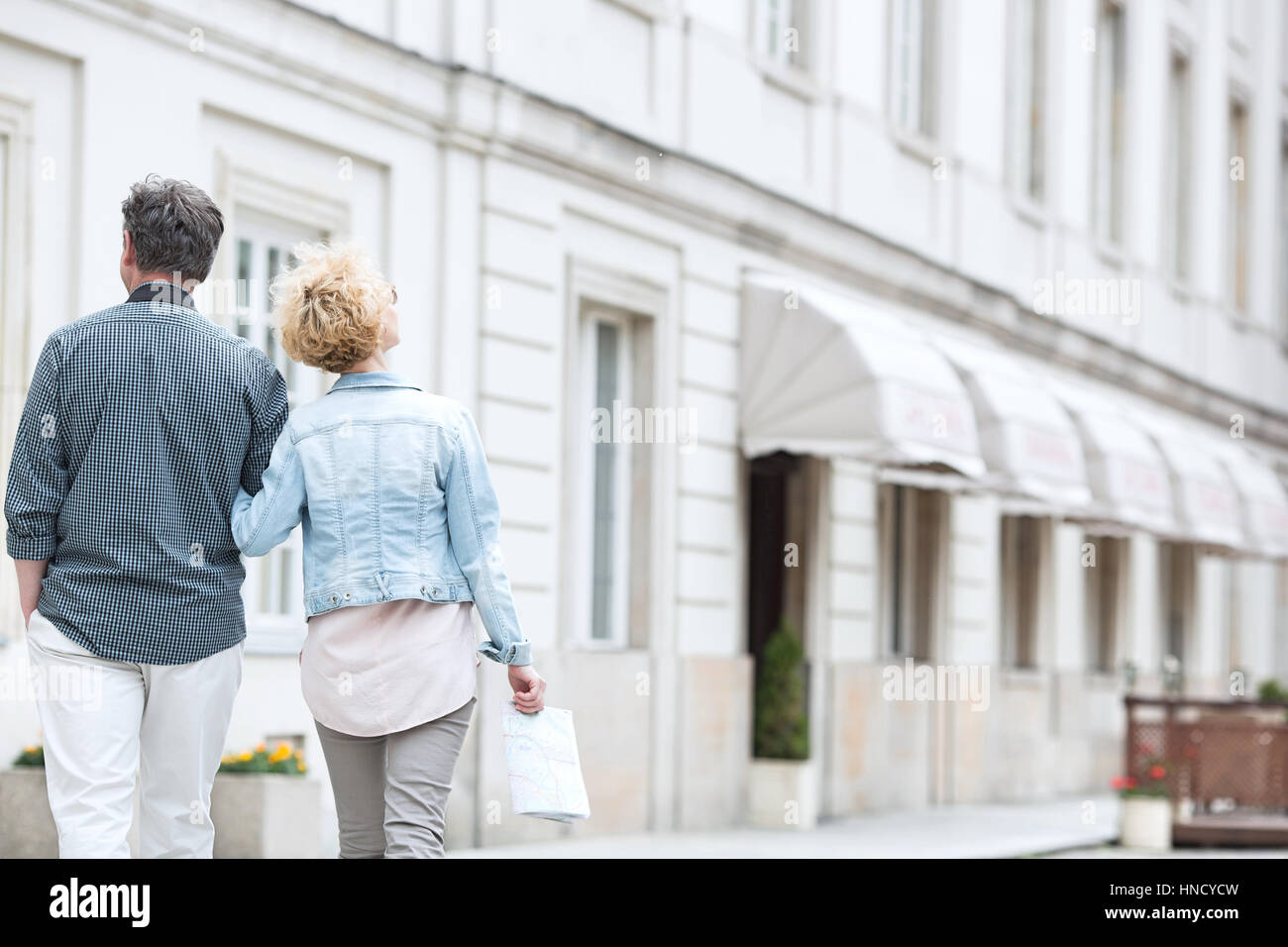 Rear view of middle-aged couple walking by building Stock Photo