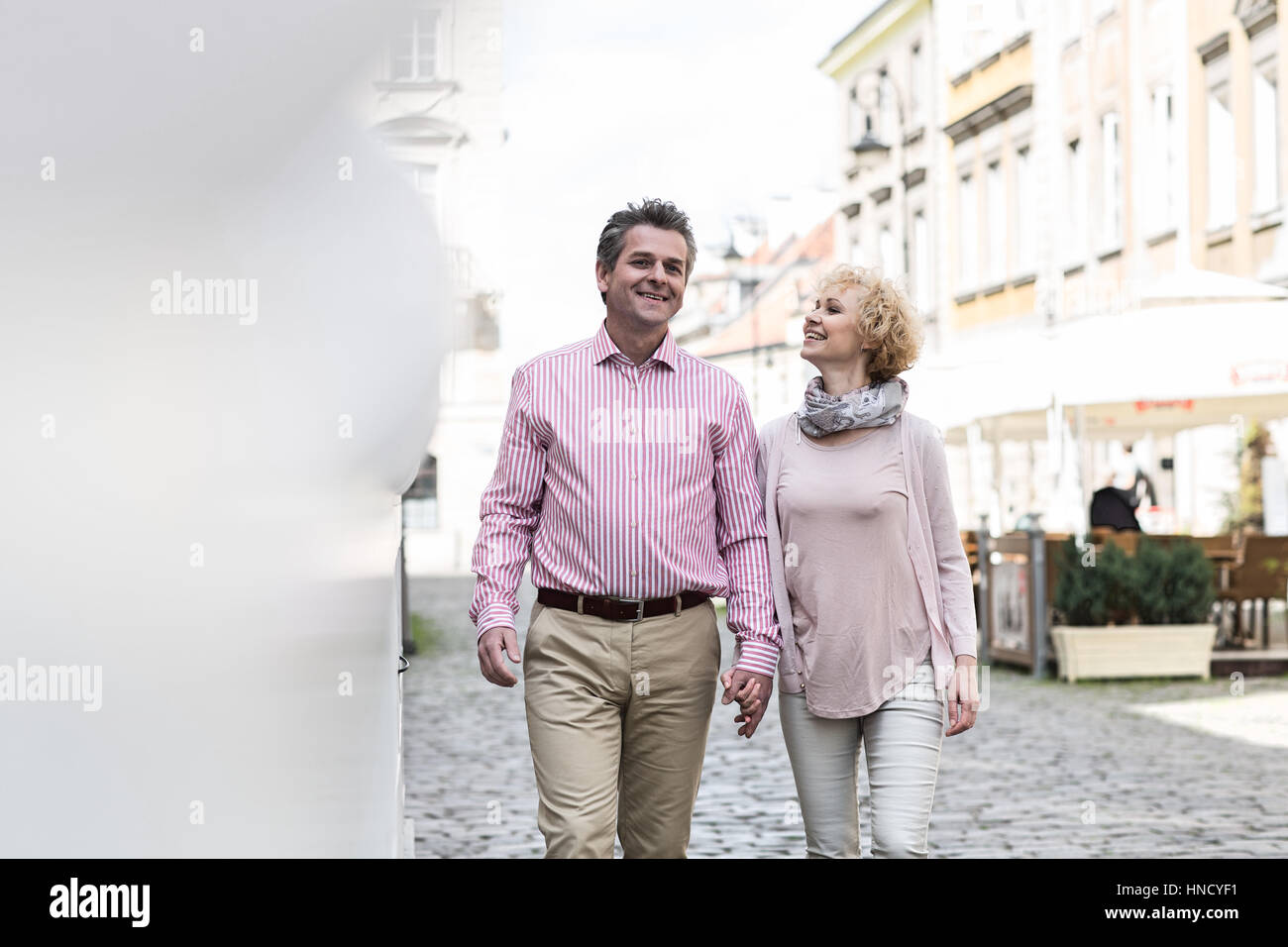 Happy middle-aged couple talking while walking in city Stock Photo