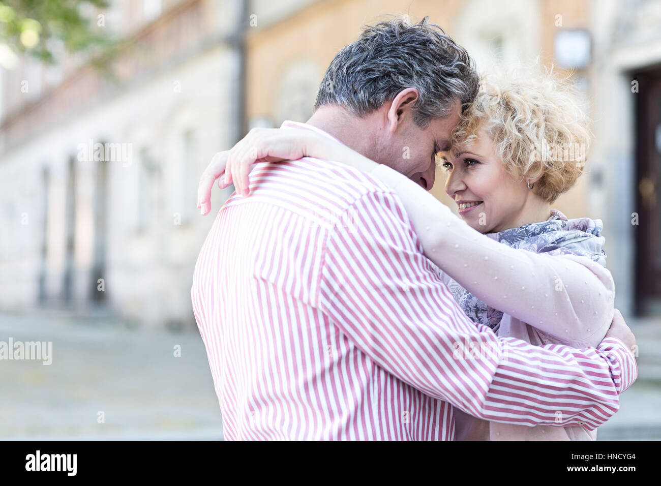Happy middle-aged couple embracing in city Stock Photo