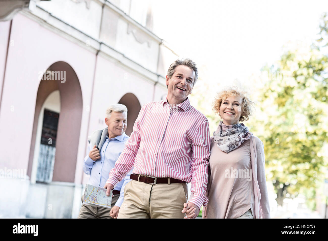Happy middle-aged couple with map walking in city Stock Photo