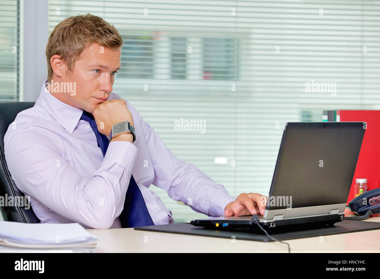 Businessman sitting with laptop at office Stock Photo - Alamy