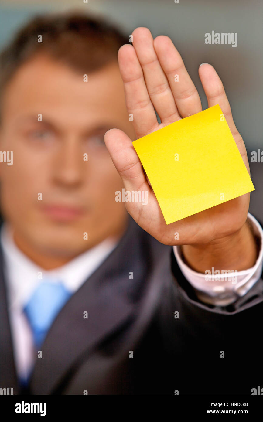 Businessman in office with blank adhesive note stuck to his hand Stock Photo