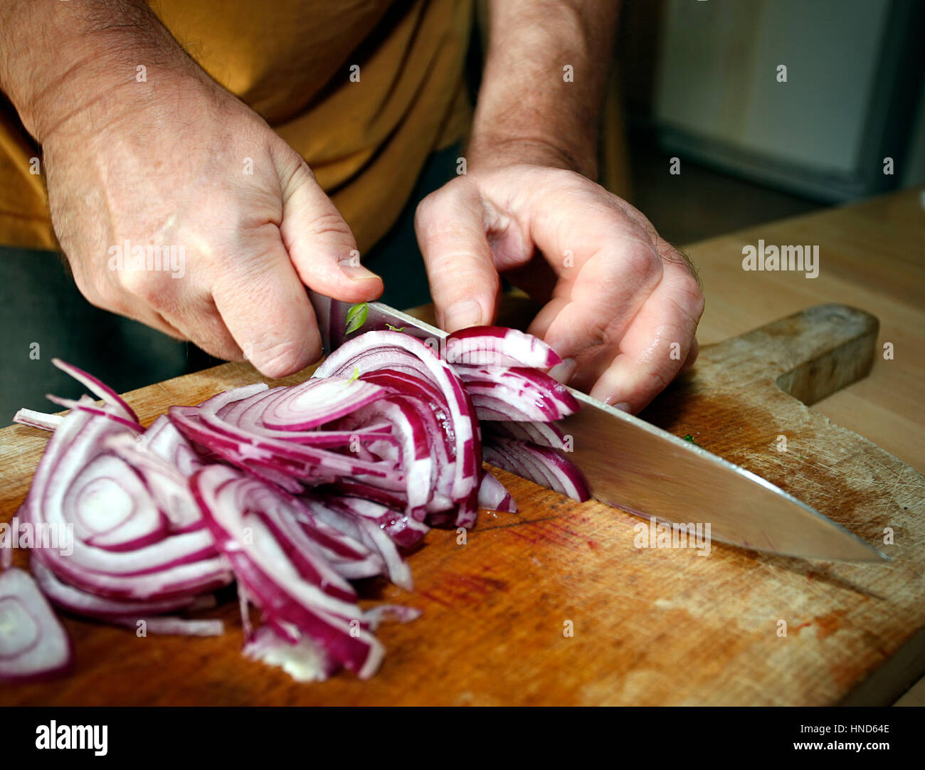 Picture of man's hands cutting red onion on wooden cutting board Stock Photo