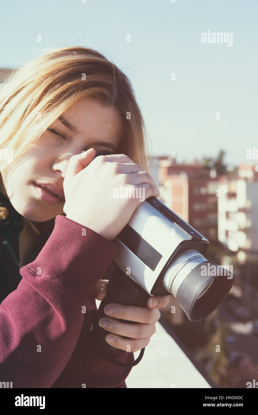 Blonde young woman shooting city from the top roof  with vintage super 8 camera Stock Photo