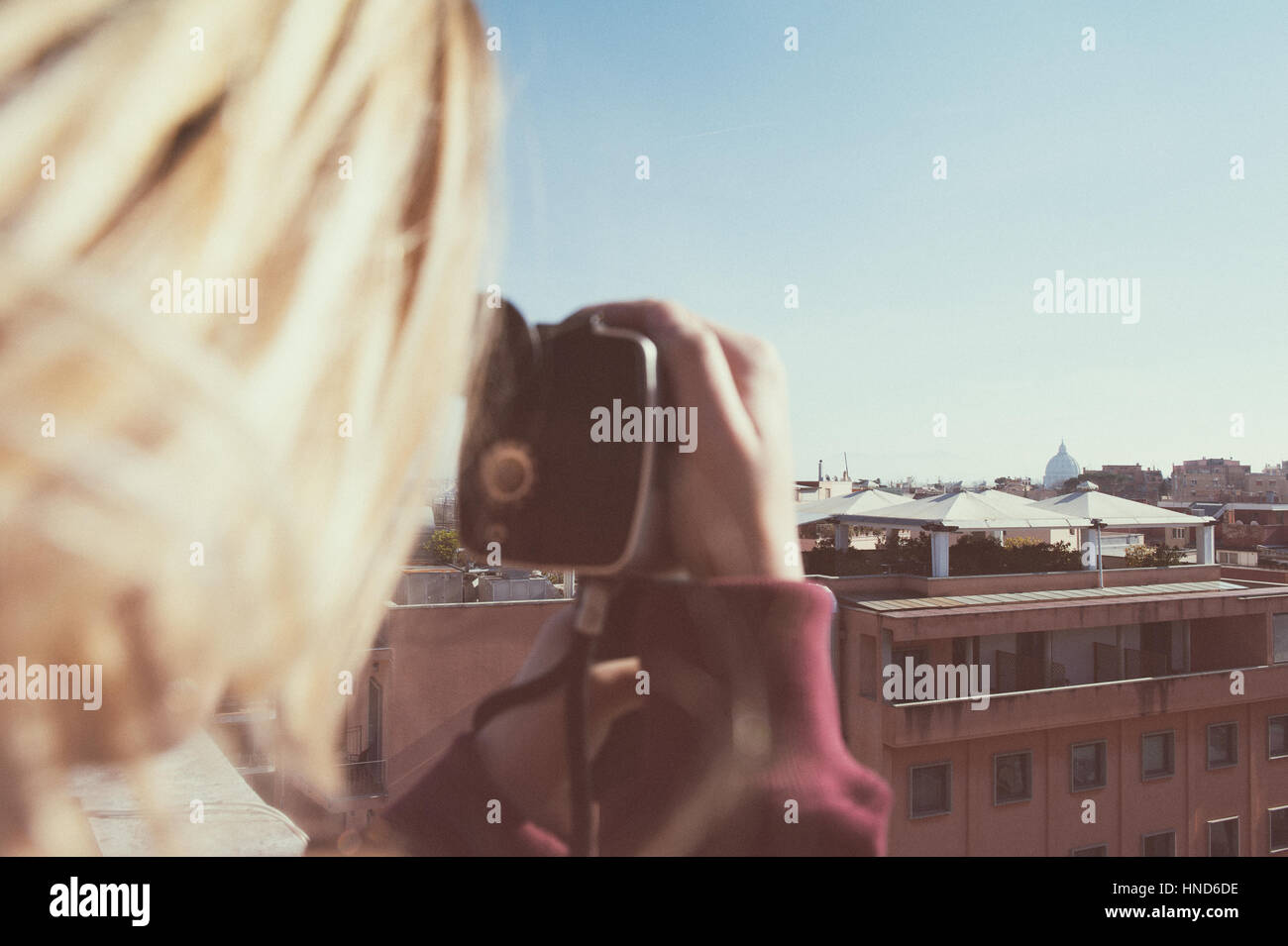 Blonde woman shooting Rome city skyline  with St Peter Dome and vintage super 8 camera Stock Photo