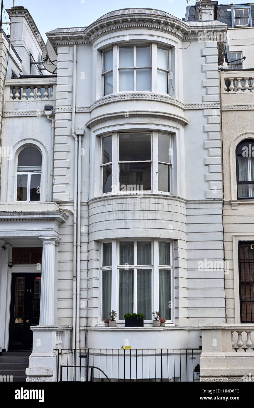 Narrow building with bay windows in an ornamented facade with ashlar walling, pillars and decorated parapets, in London city Stock Photo
