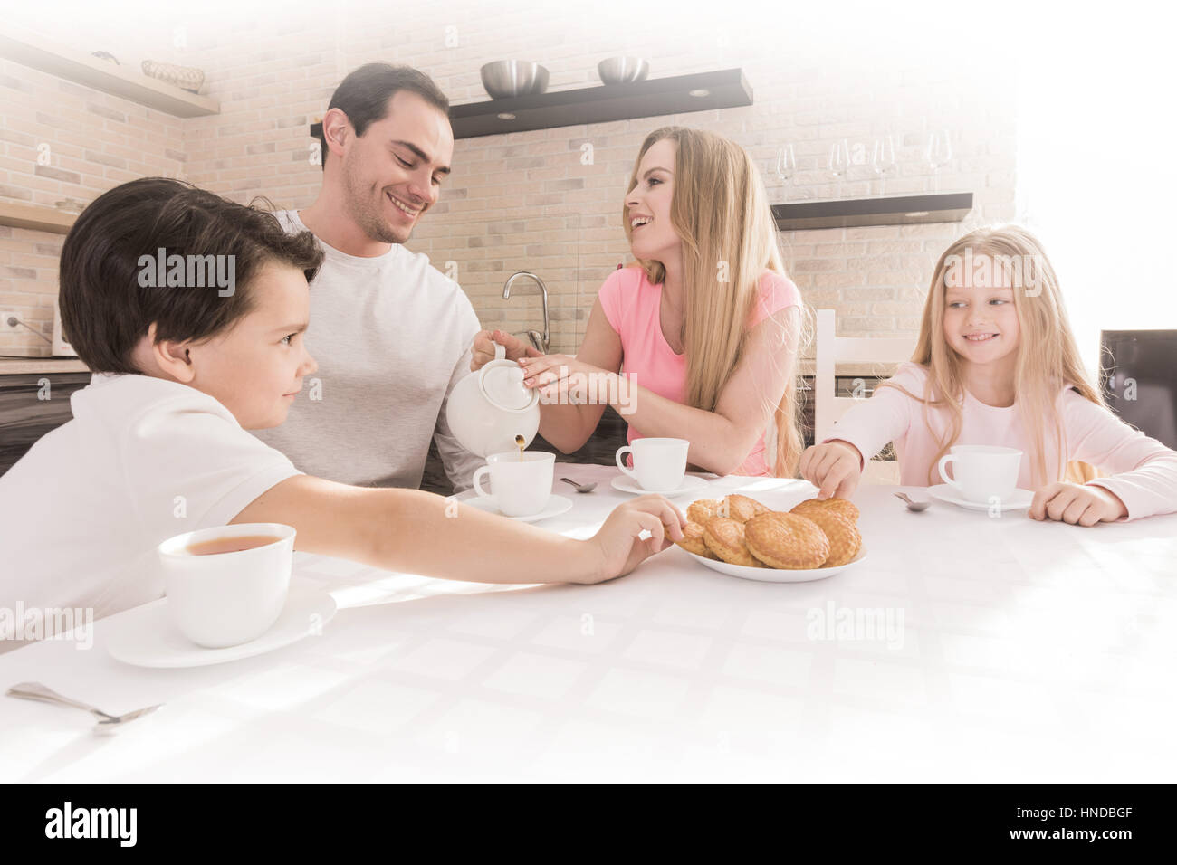 Family eating cookies with tea in the kitchen at home Stock Photo