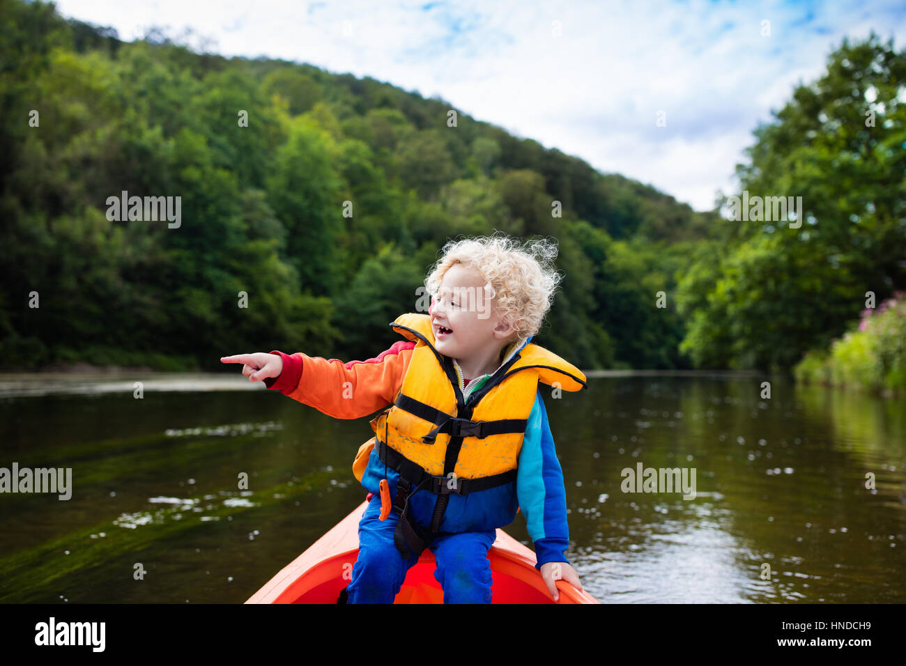 Happy kid enjoying kayak ride on beautiful river. Little curly toddler ...