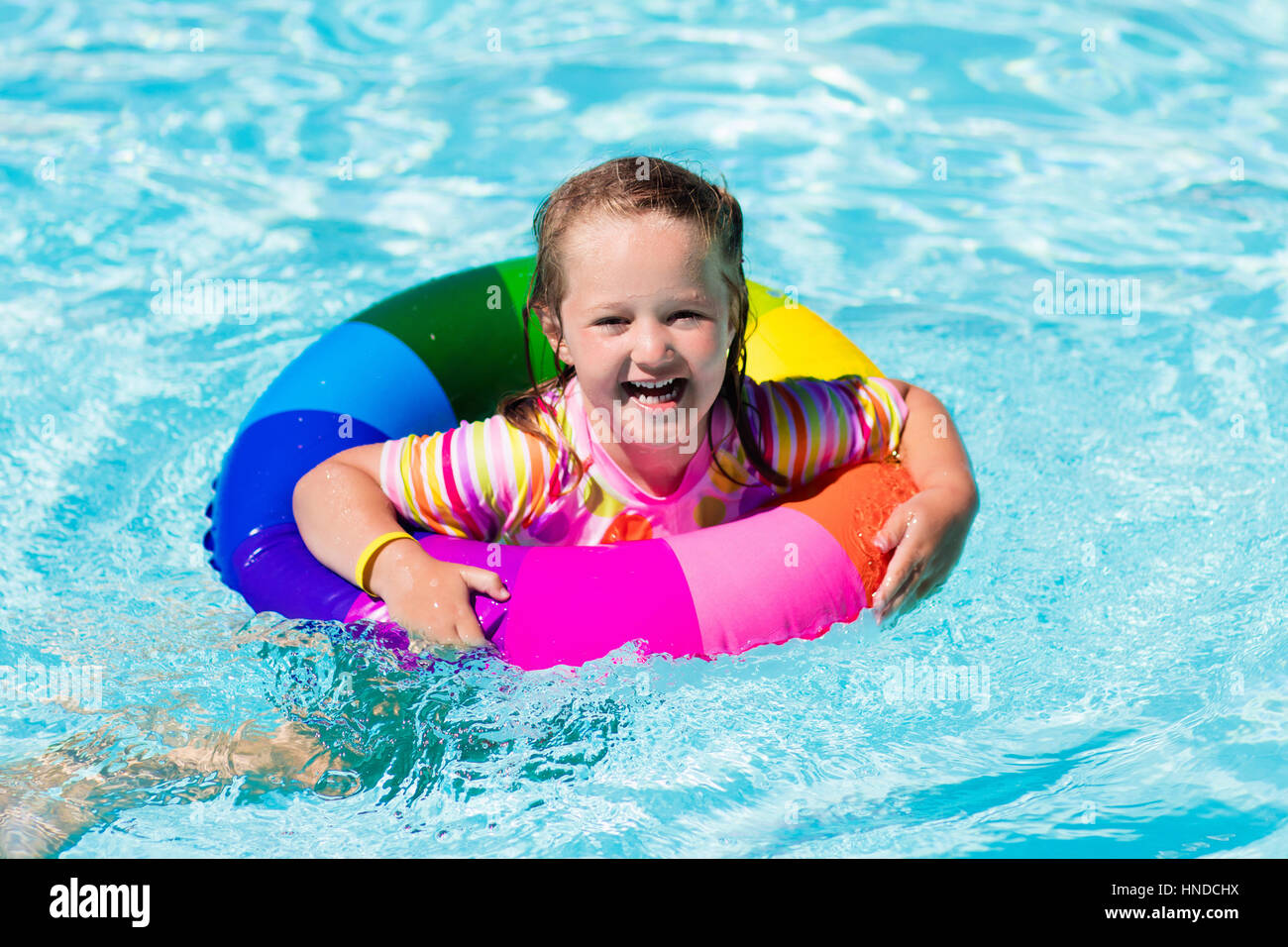Happy little girl playing with colorful inflatable ring in outdoor ...