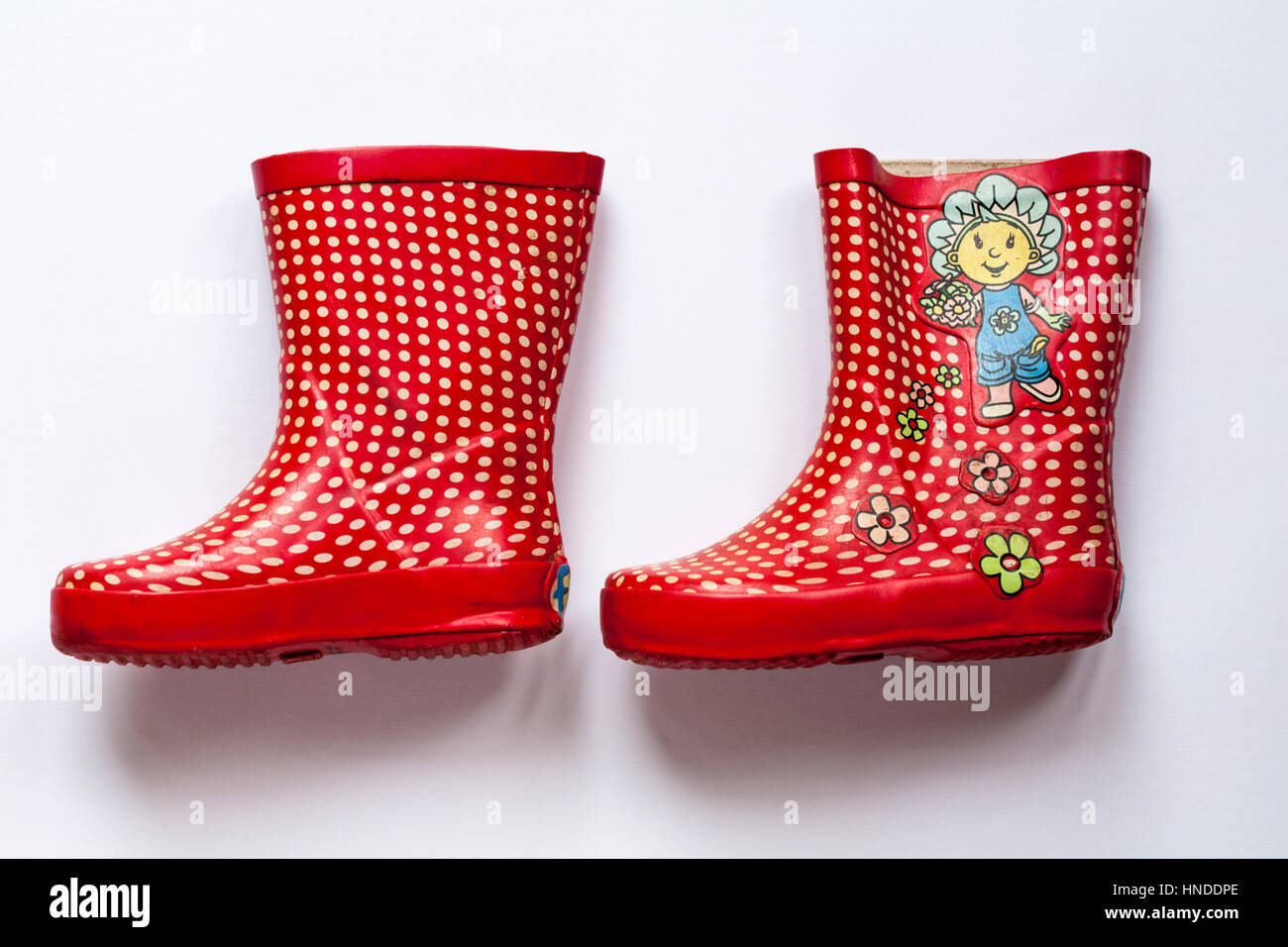 Well loved used pair of children's red polka dots wellie boots with fifi and the flowertots on  isolated on white background Stock Photo