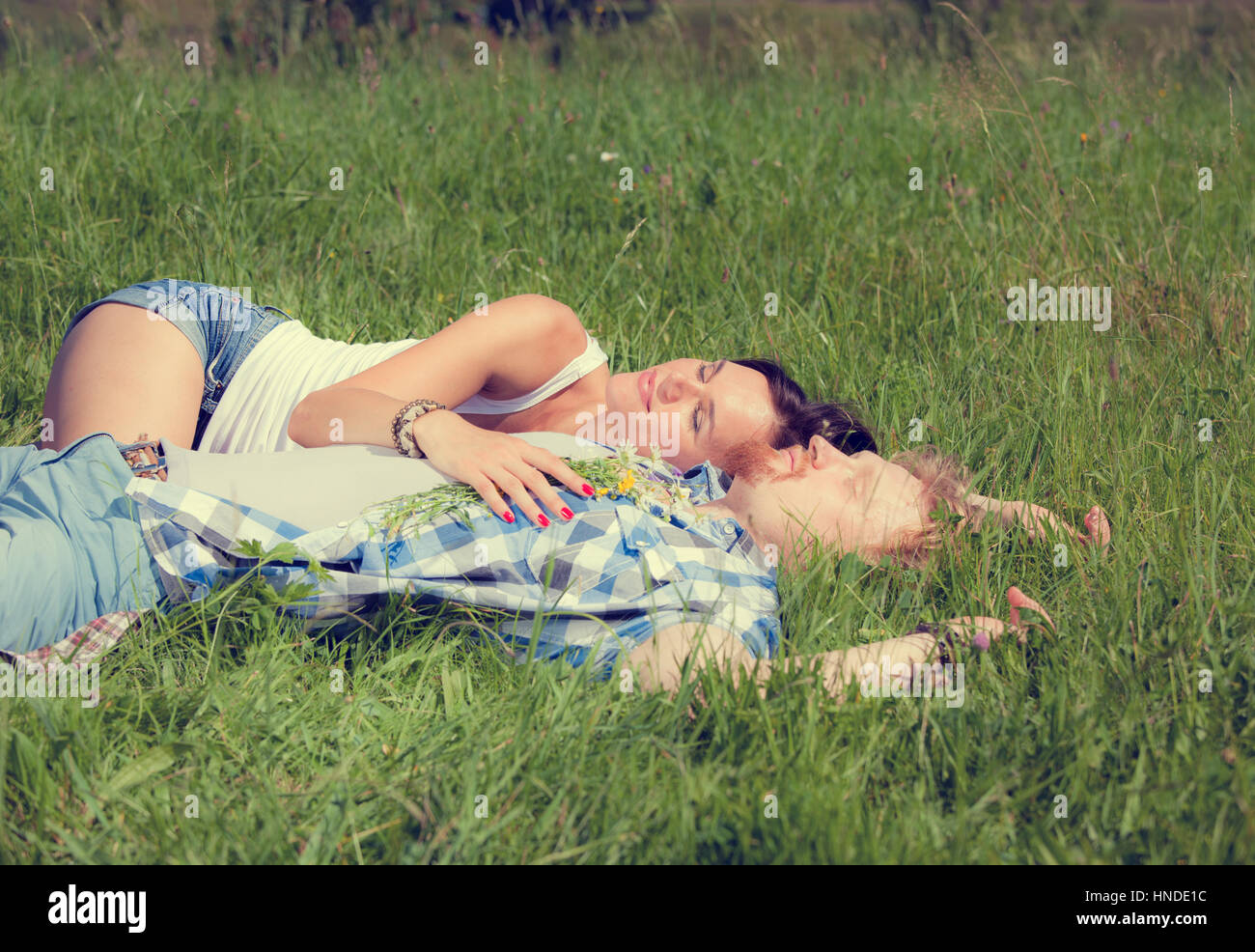 Happy beautiful couple in love lying on the green grass meadow Stock ...