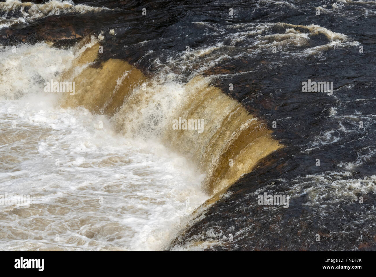 River water coloured by humic acid falls over a ledge in the Humber