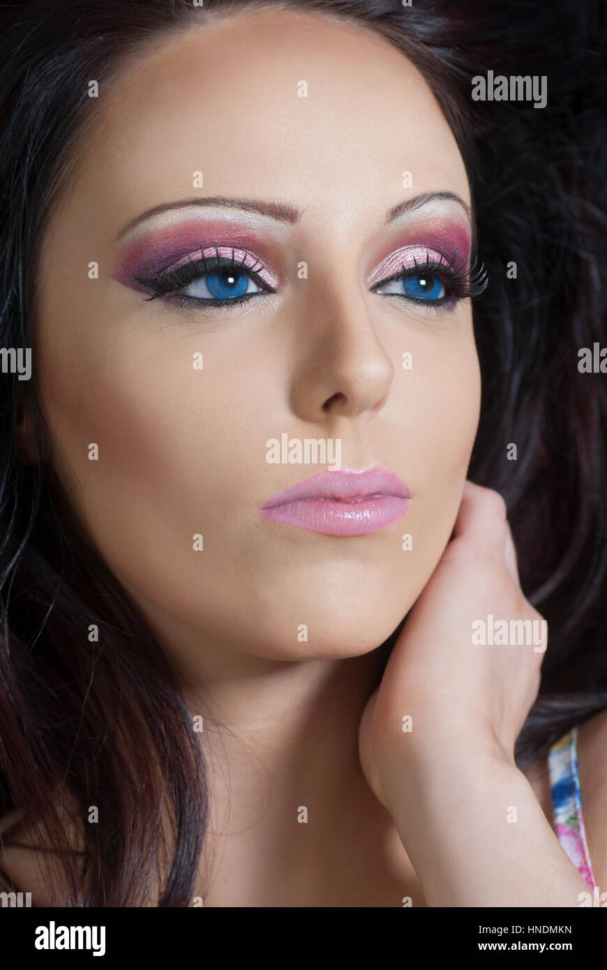 Beaitful woman with blue eyes wearing pink eyeshadow makeup hand touching  face looking away Stock Photo - Alamy